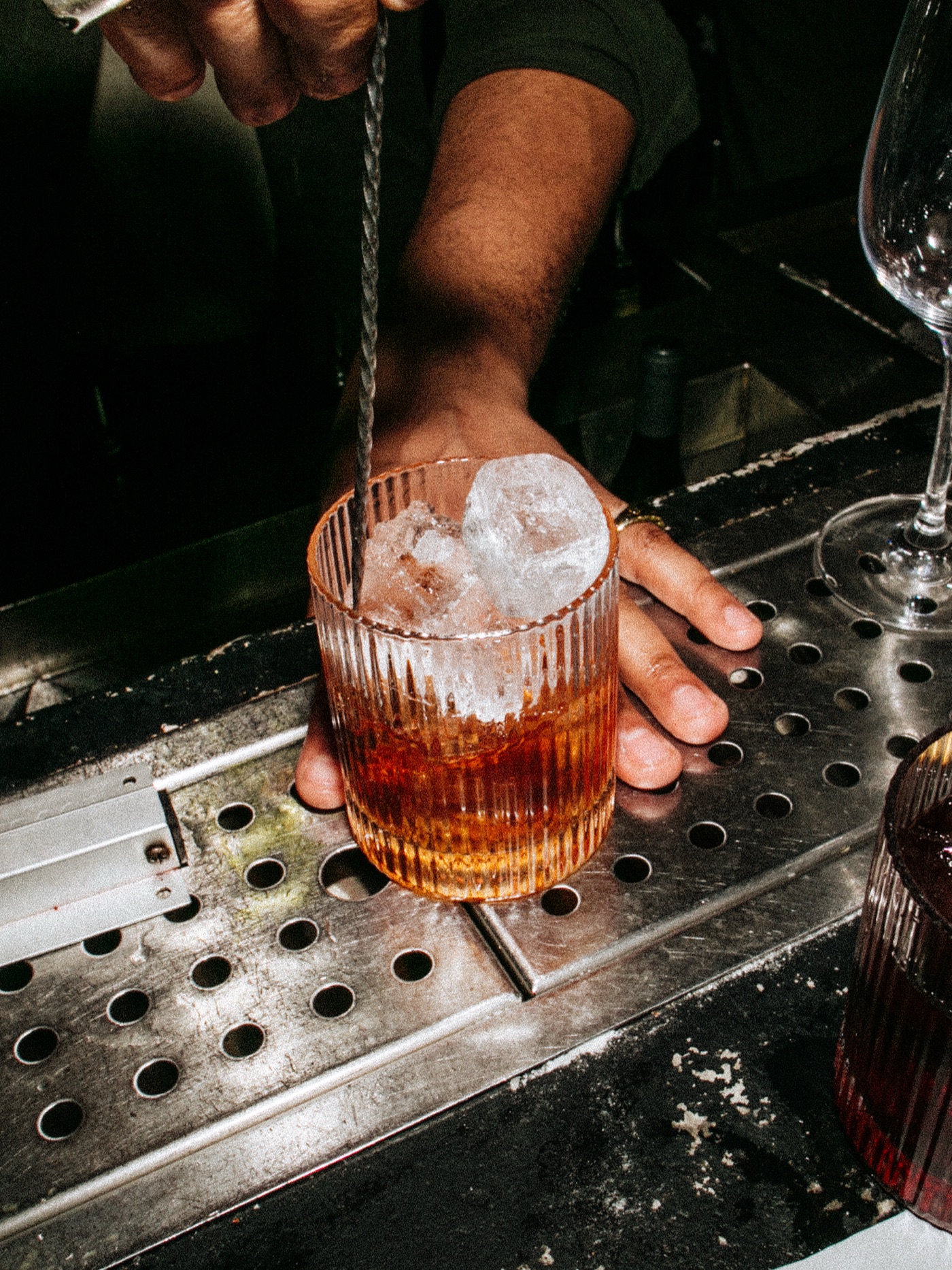 Bartender stirring a cocktail in a ribbed glass on the bar