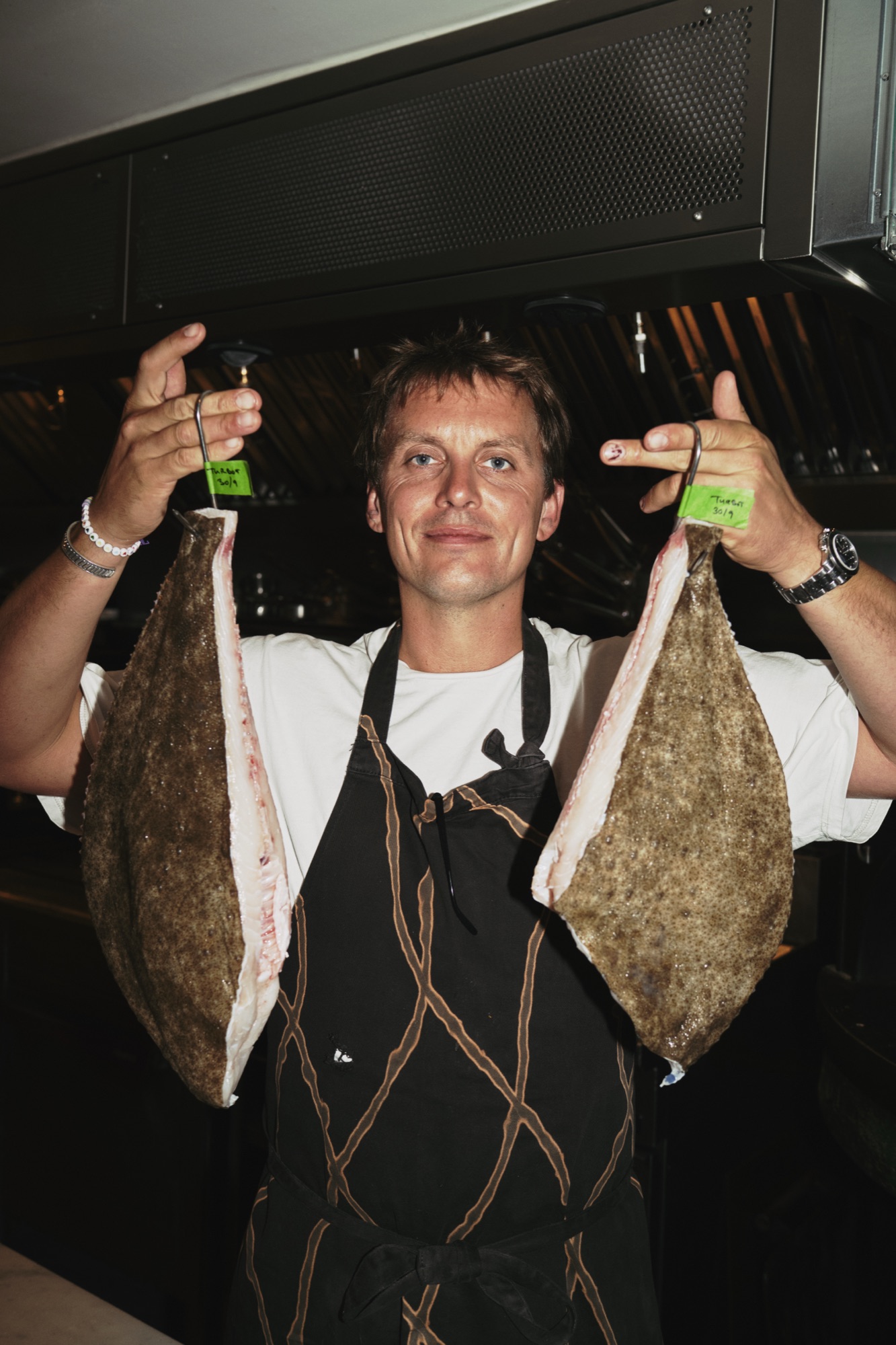 Thomas Straker holding two flatfish in the kitchen